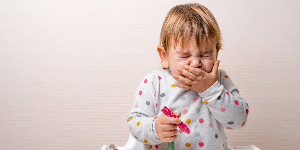 Malé dieťa, ktoré má nádchu, kýcha a zakrýva si ústa