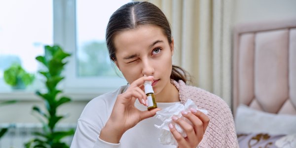 žena , ktorá má nádchu, si do nosa aplikuje nosný sprej